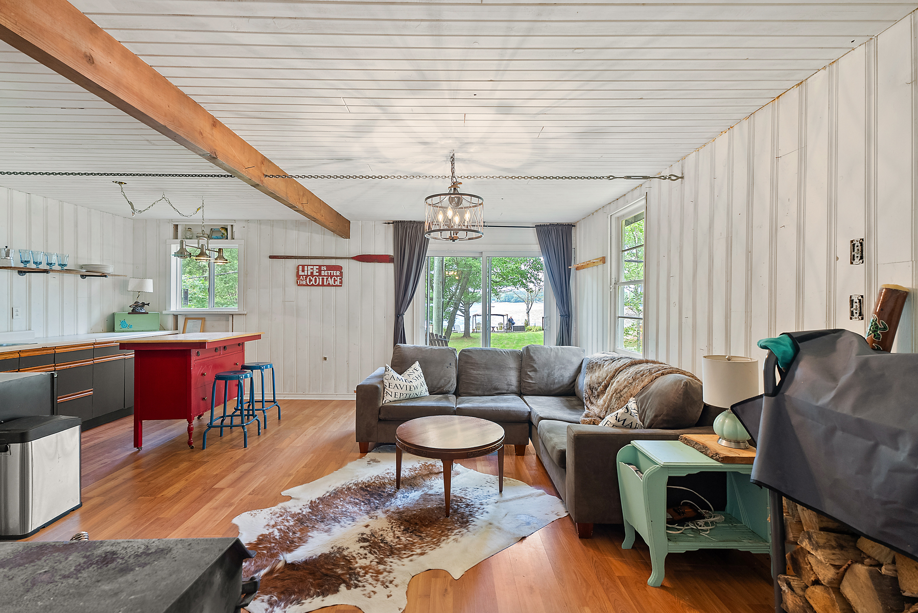 Grey couches face a small round wood table on a cow hide rug