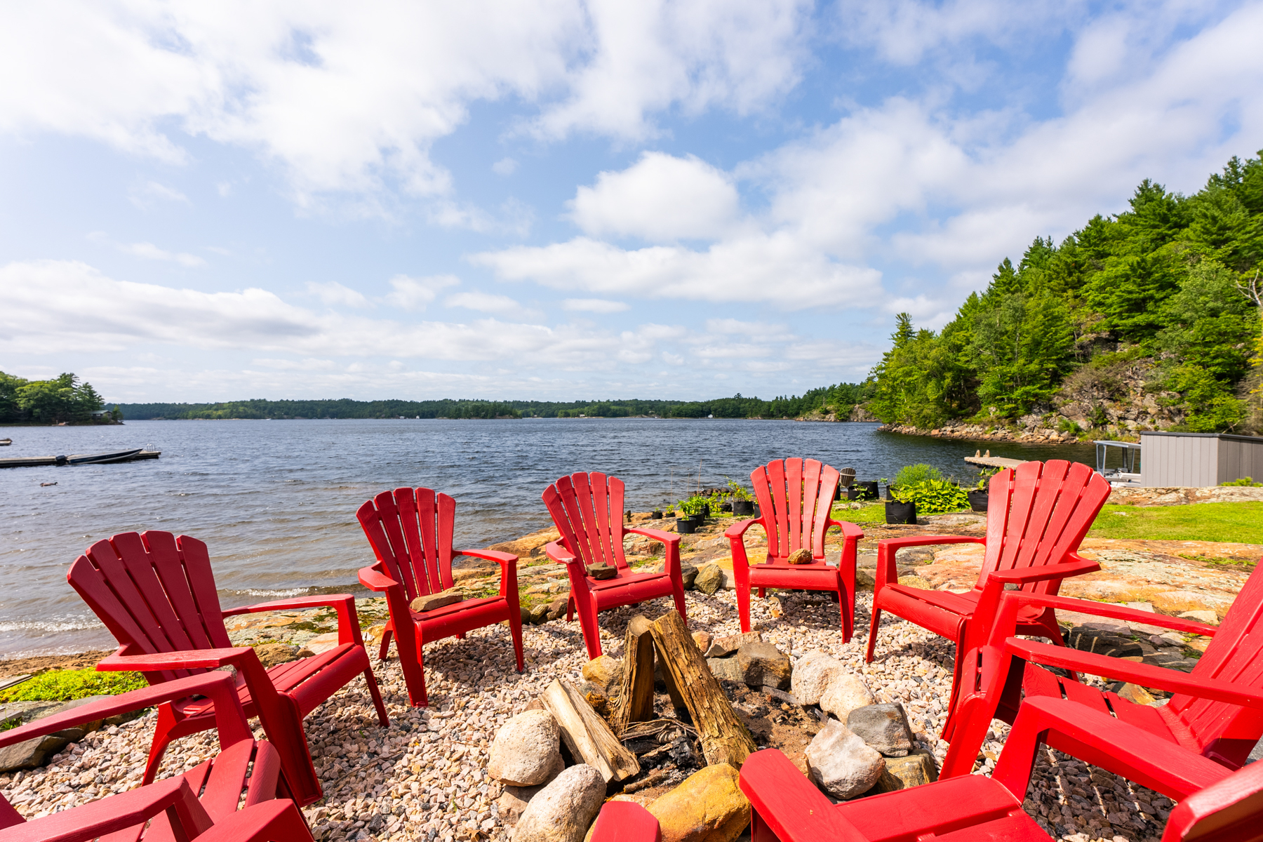 A fire pit with red Muskokas chairs surrounding it