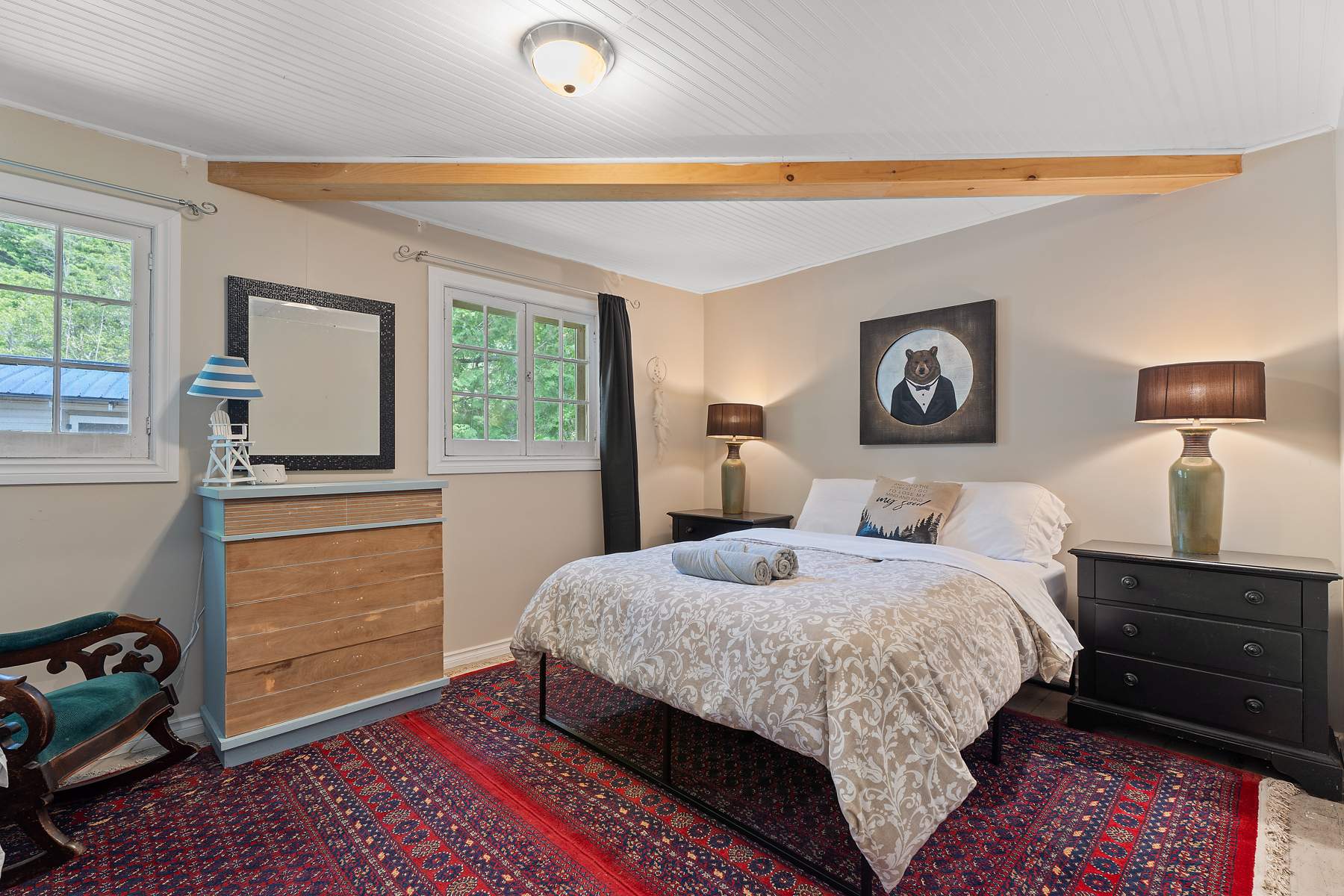 A large bed on a red patterned rug