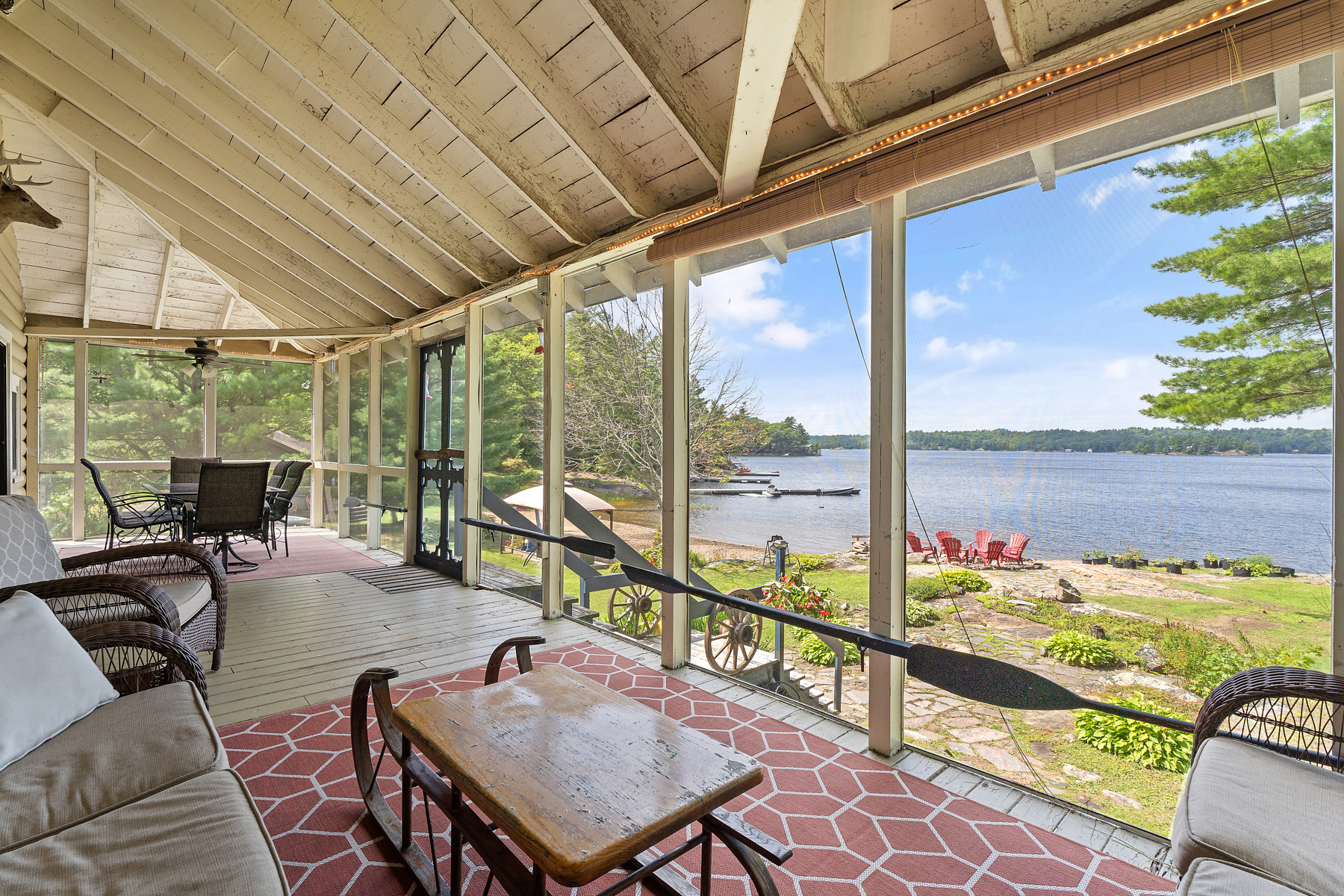 A couch on a pink carpet in a bright screened-in porch