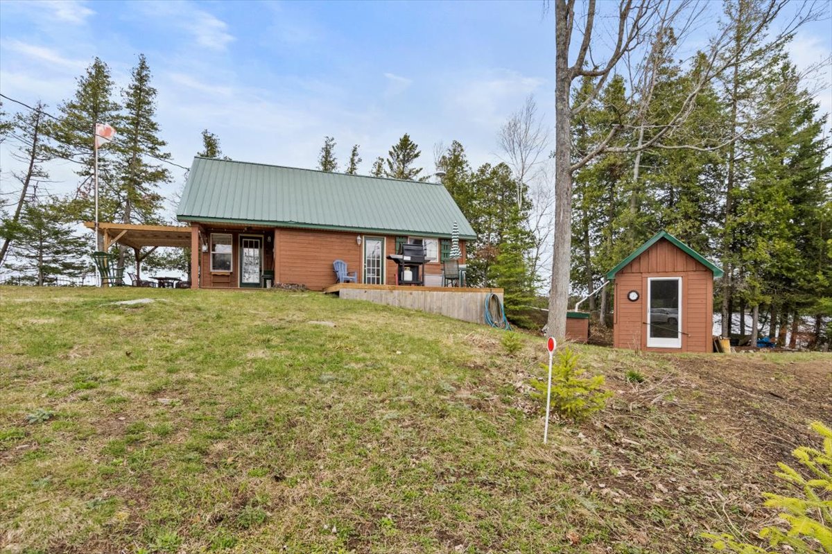A log cabin with a green roof on a grassy lawn