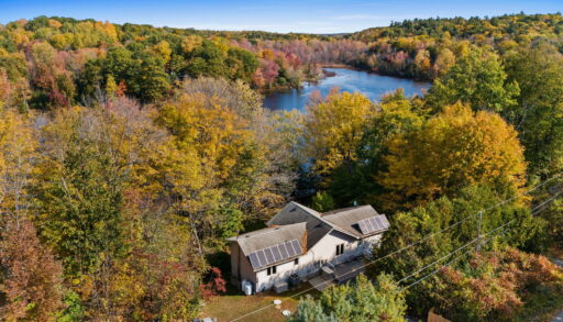 Overhead view of a grey cottage nestled amongst autumn trees