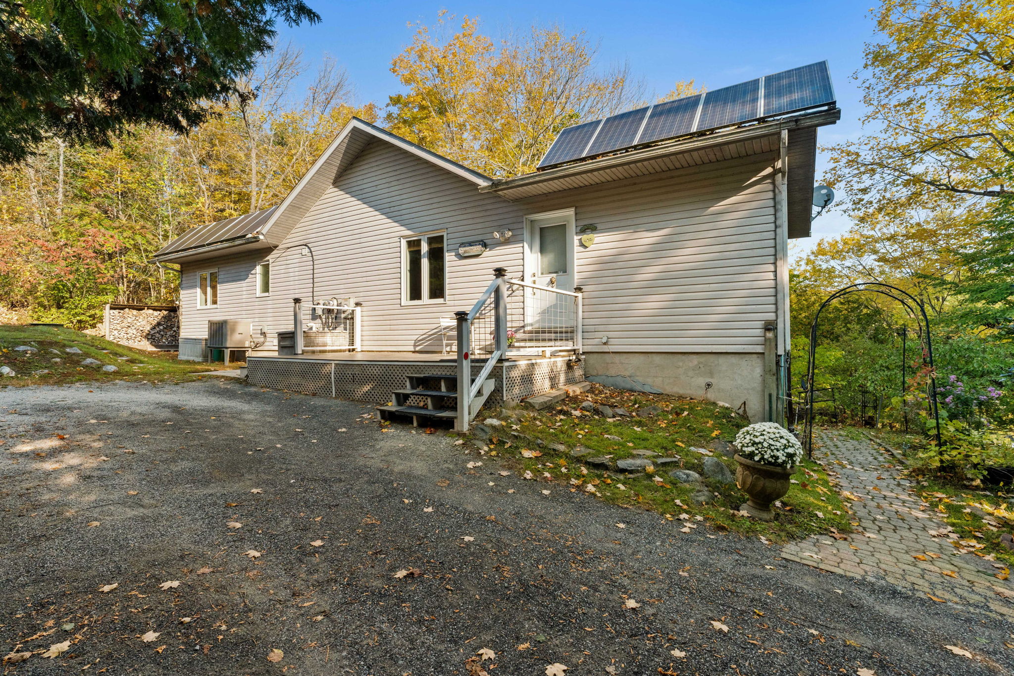 A beige panelled cottage with solar panels off a driveway