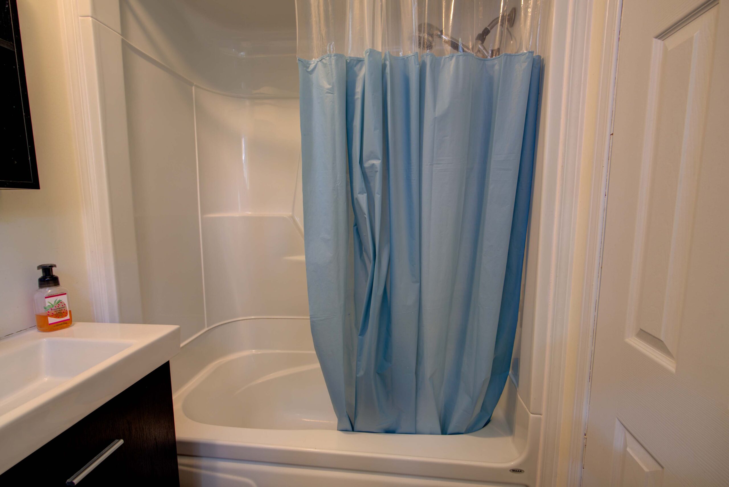 A white shower with a blue shower curtain