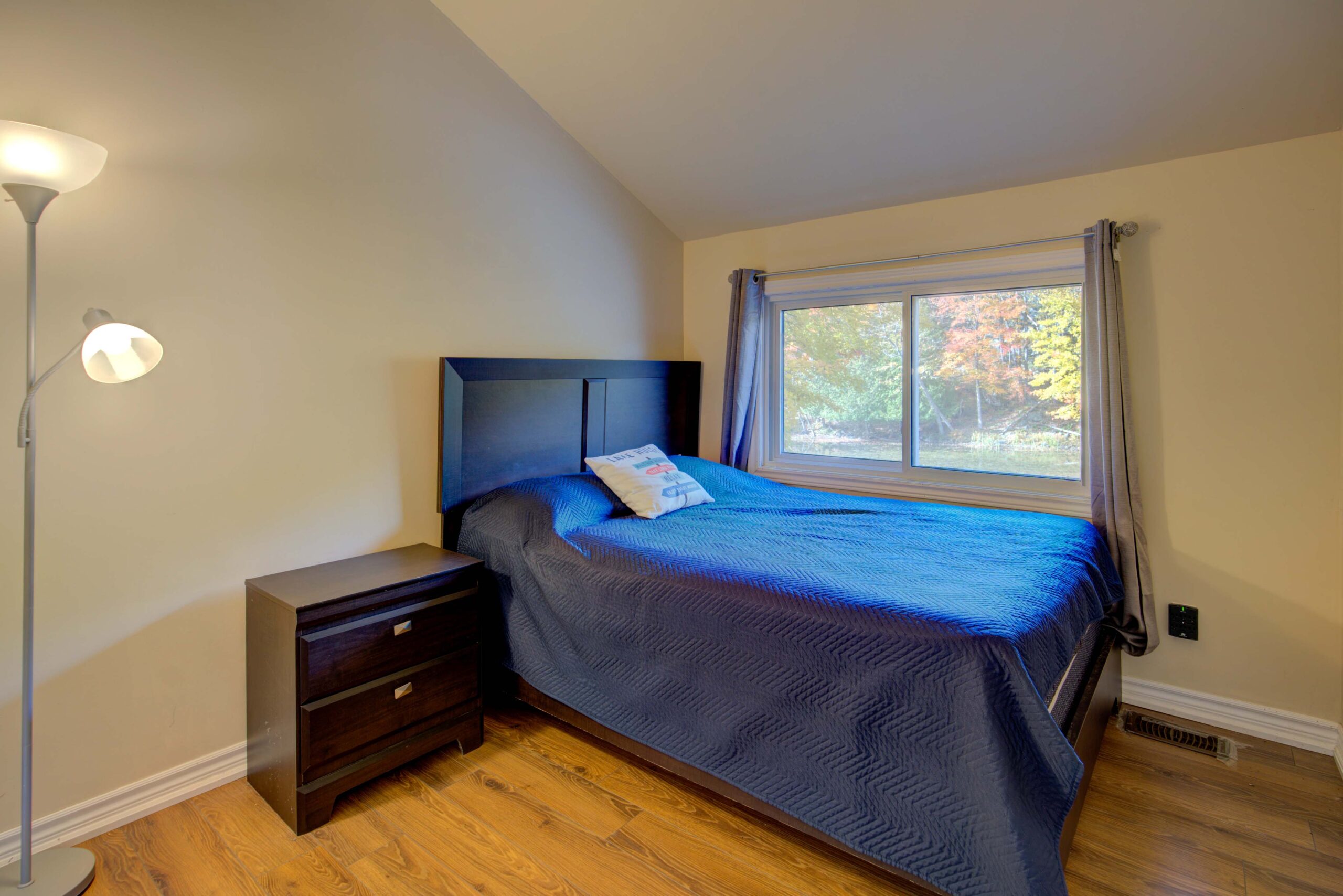 A large bedroom with a dark blue duvet next to a window