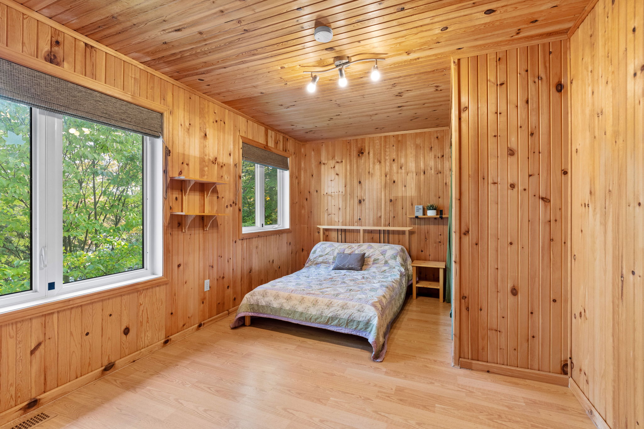 A white bed set into a wood panelled bedroom
