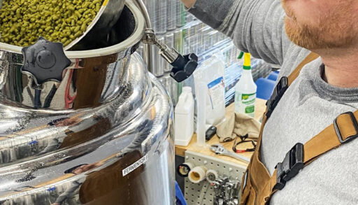 a person pouring hops into a fermentation tank