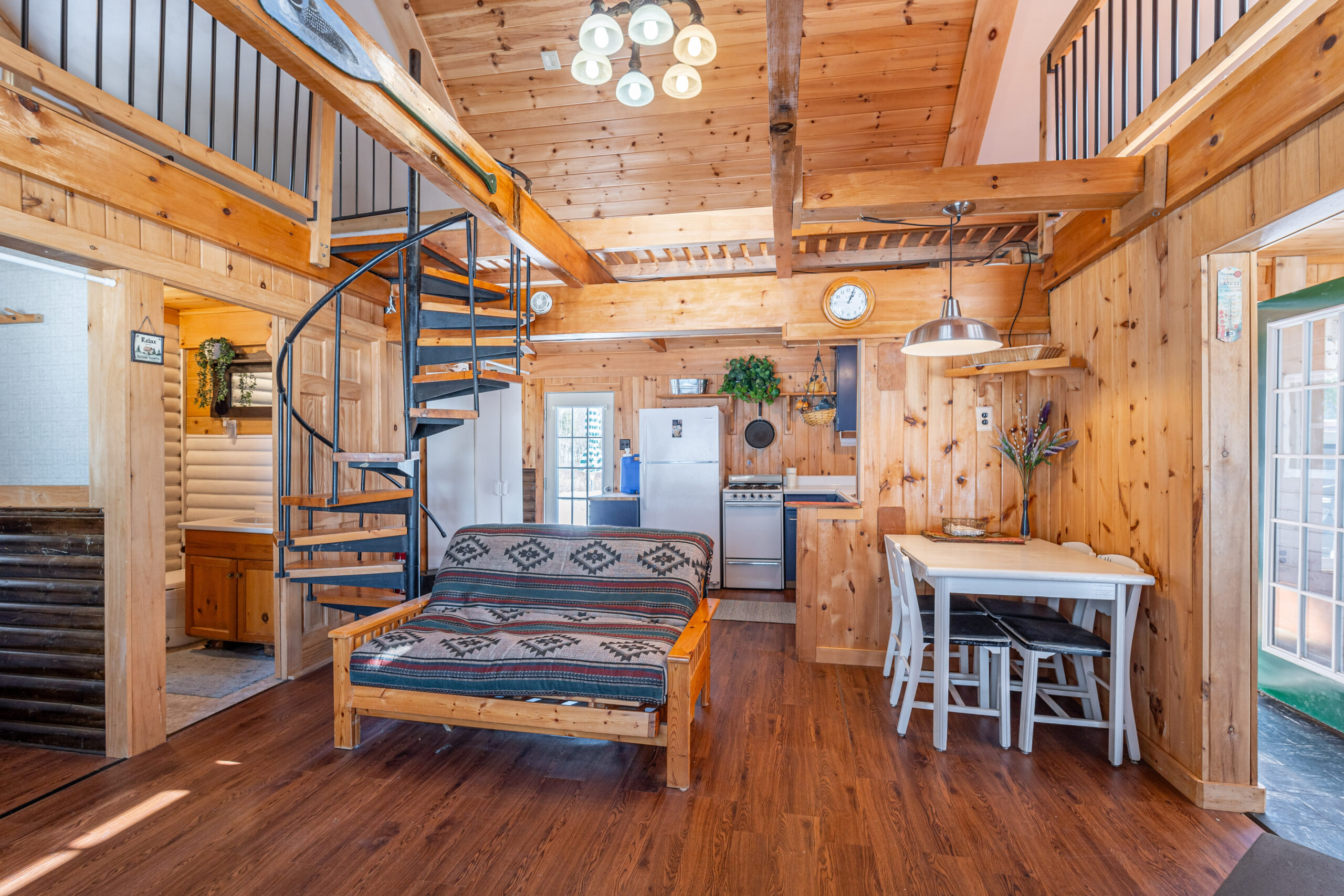 A patterned couch in the centre of a log room with a spiral staircase