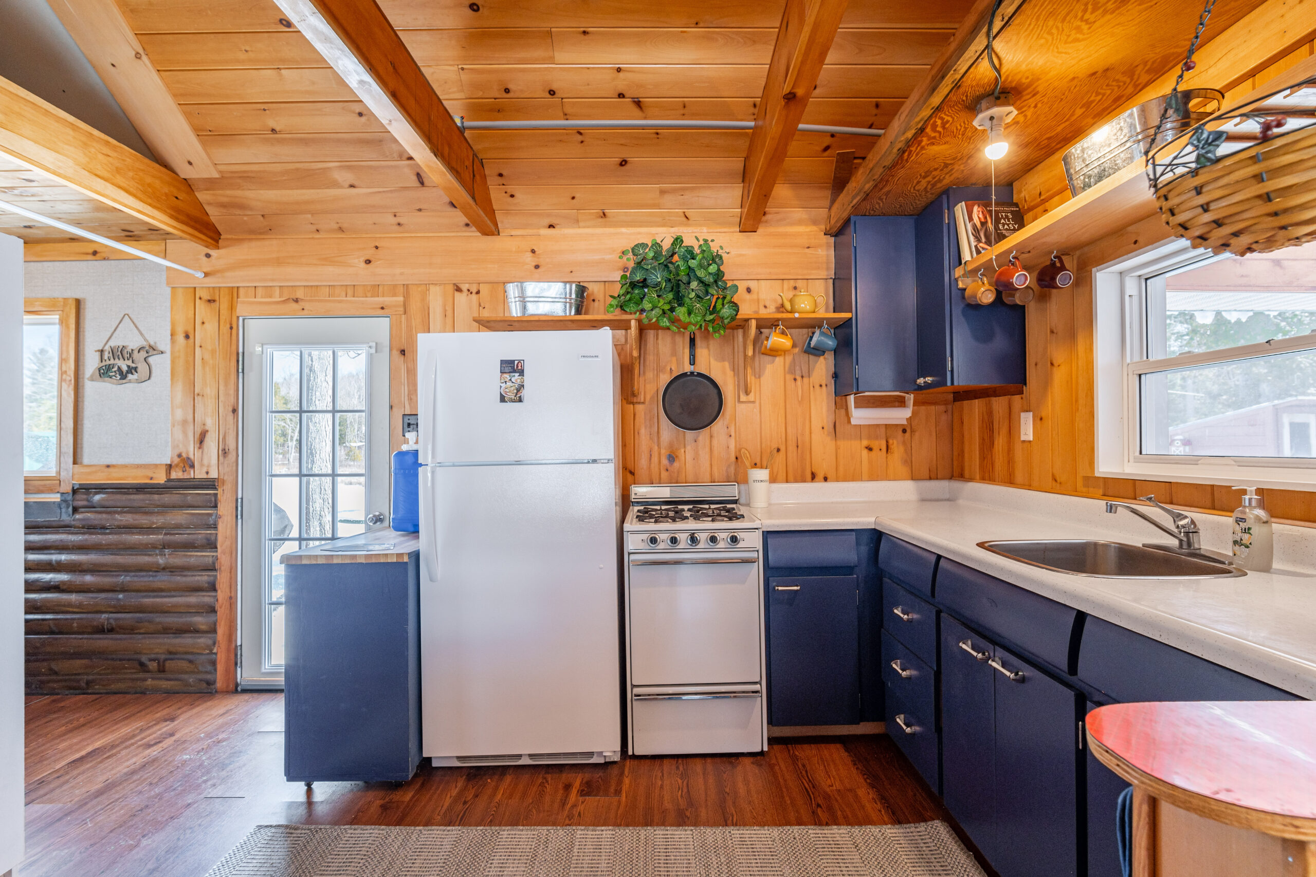 A small kitchen in a wood cabin with blue cabinets and white appliances