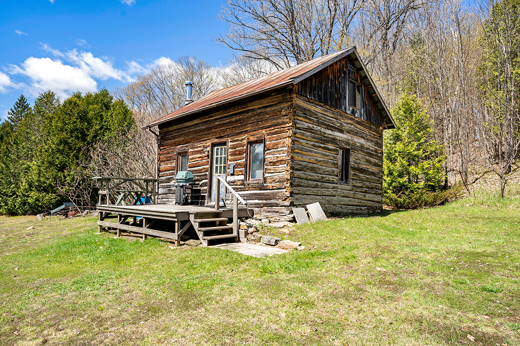 A two-story log cabin in a grassy area