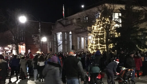 a lit-up christmas tree with folks gathered around