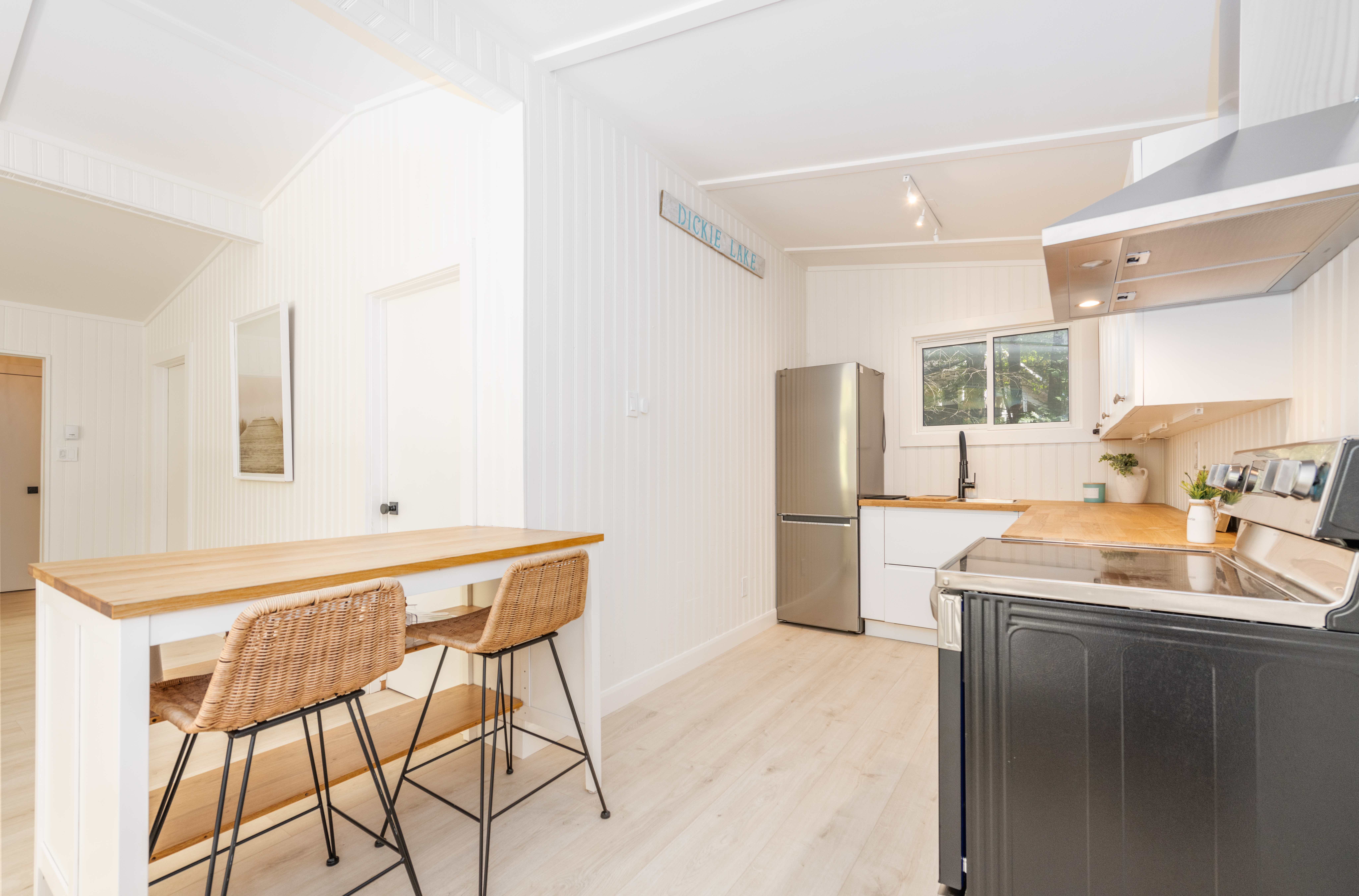 A wood breakfast bar is across from a white kitchen