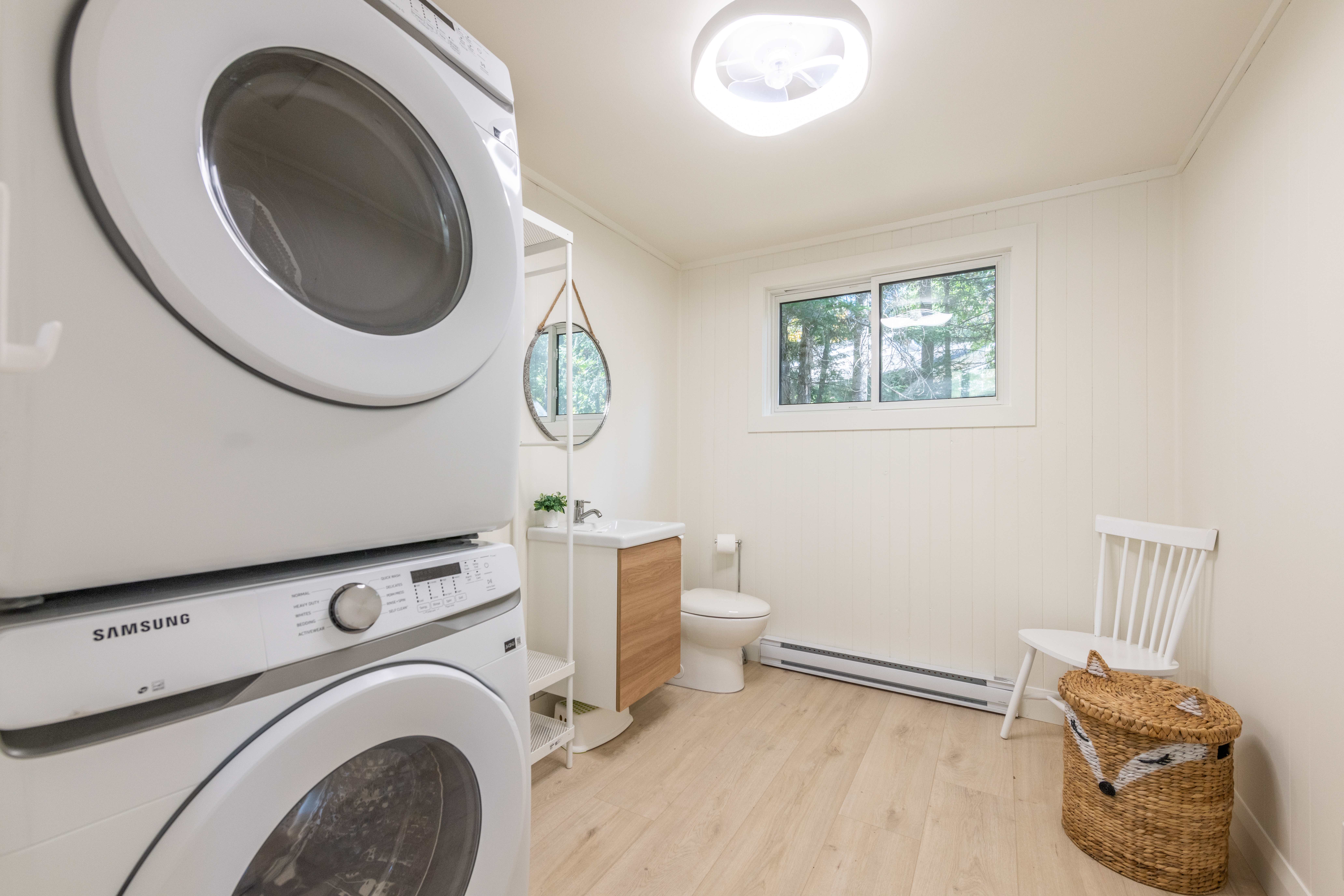 Stacked white laundry machines sit beside a bathroom