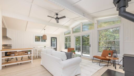 A white couch faces a wall of bright windows in a white room
