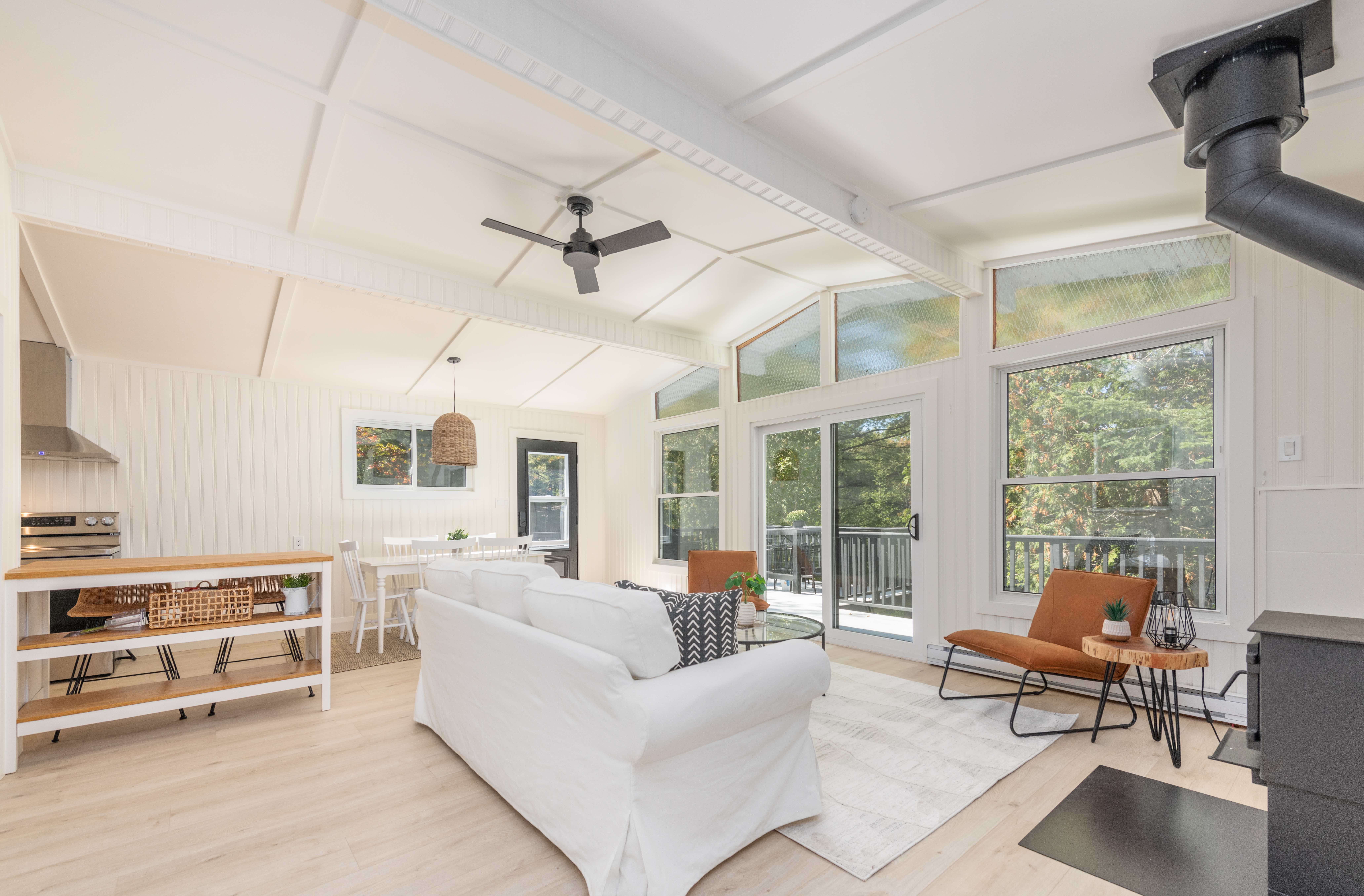 A white couch faces a wall of bright windows in a white room