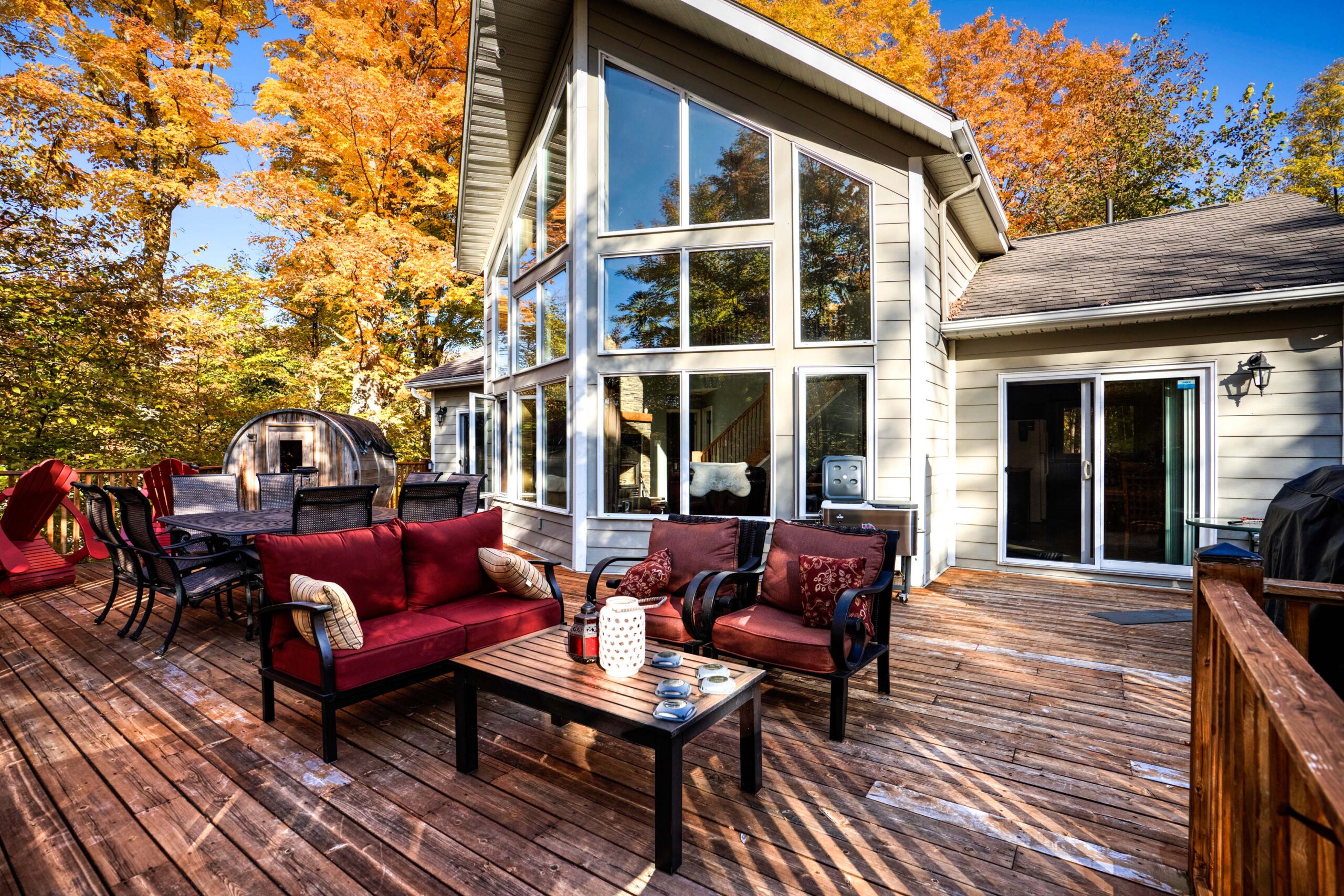 A red patio set on a new deck next to a huge cottage with floor-to-ceiling windows