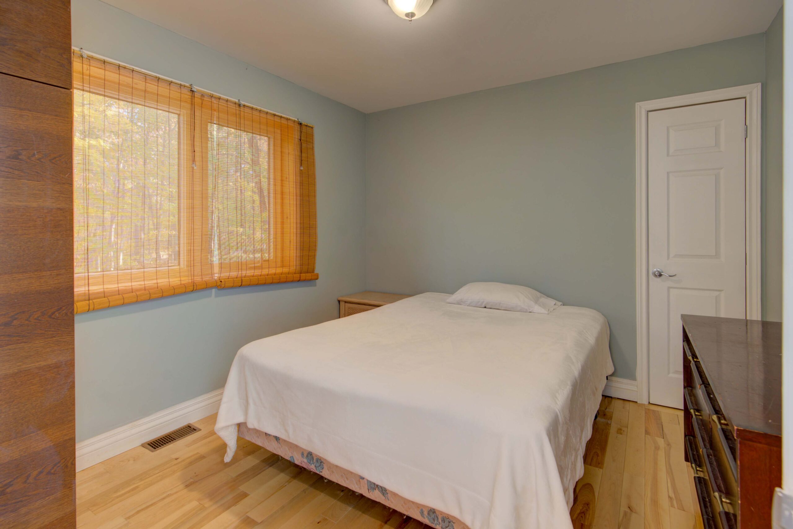 A large bed with a white bedspread in a blue room