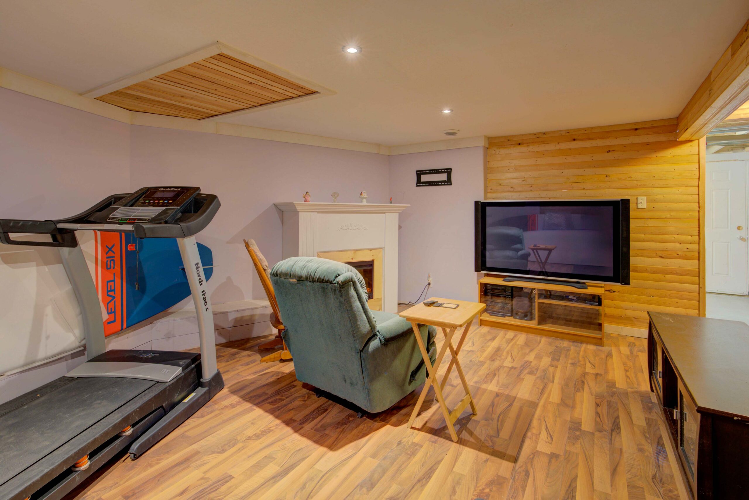 A green chair faces a built-in fireplace and TV in an empty room