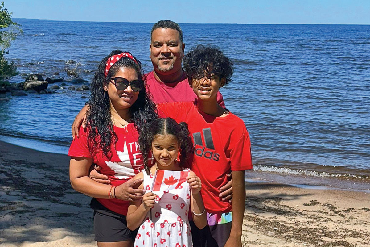 a family of four smiles for a photo on the beach