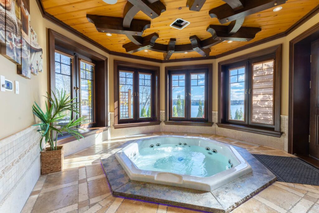 An octogon-shaped hot tub in a round room with windows all around