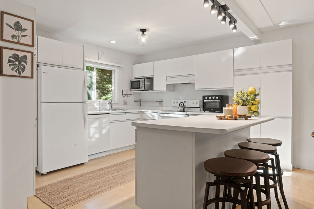 A white kitchen with a large island and light coloured wood floors