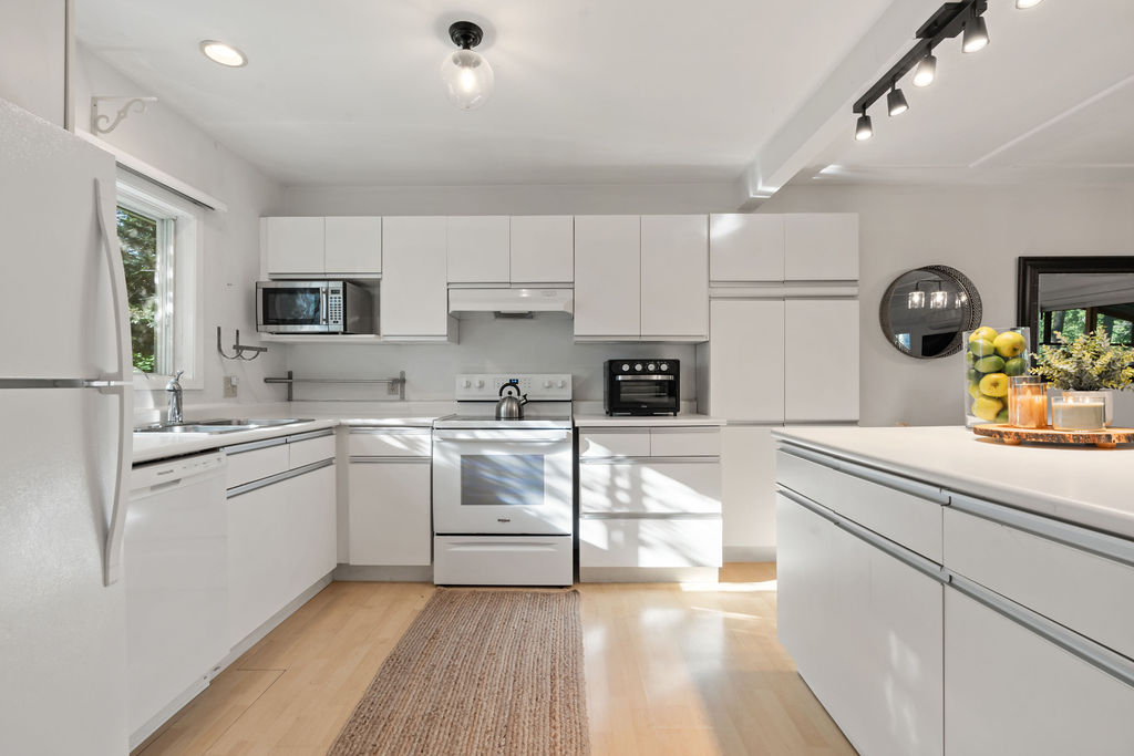 A white kitchen with light coloured wood floors