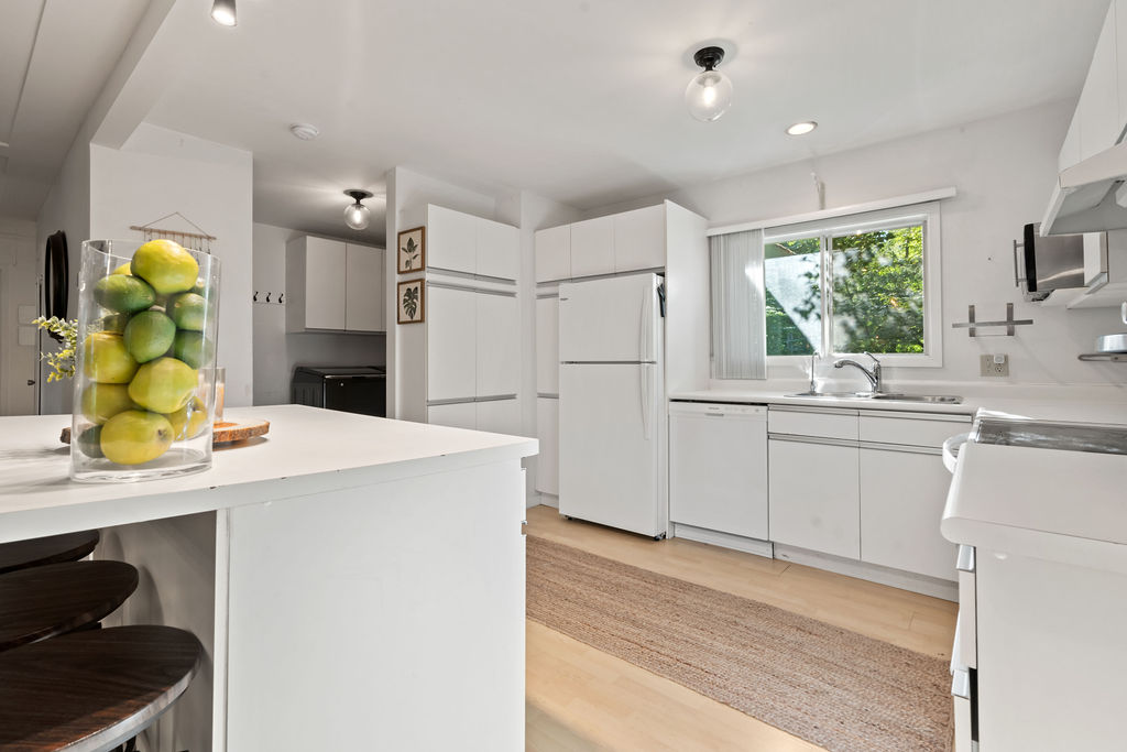 A white kitchen with light coloured wood floors