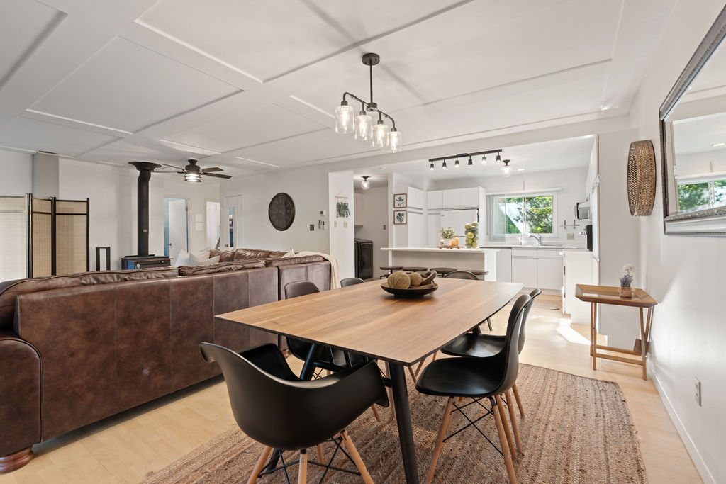 A small dining table with black chairs beside the back of a brown leather couch