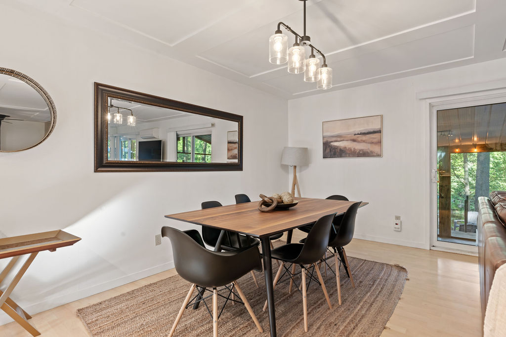A small wood table with black chairs. A rectangular mirror hangs beside it