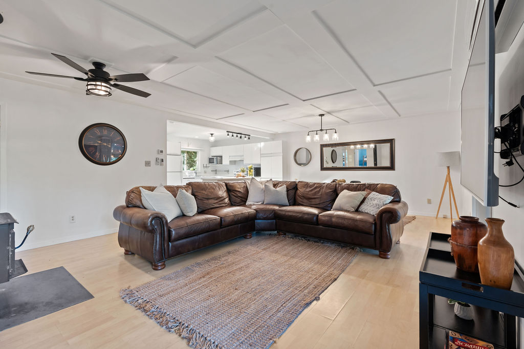 A brown leather couch with white cushions on a large carpet