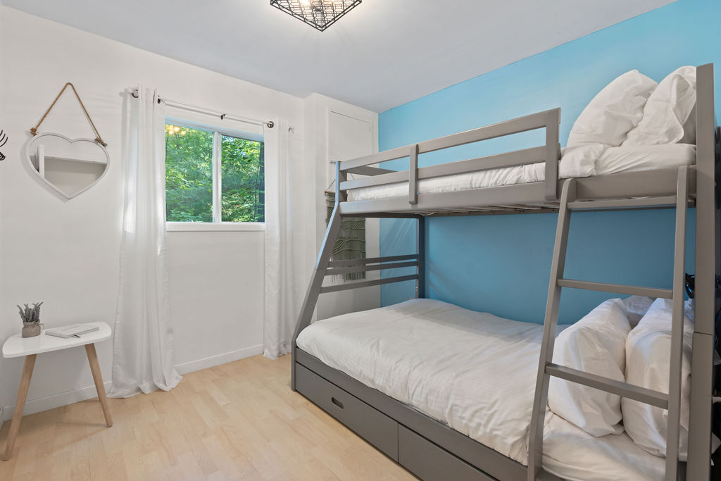 A grey bunk bed in a white and bright blue room