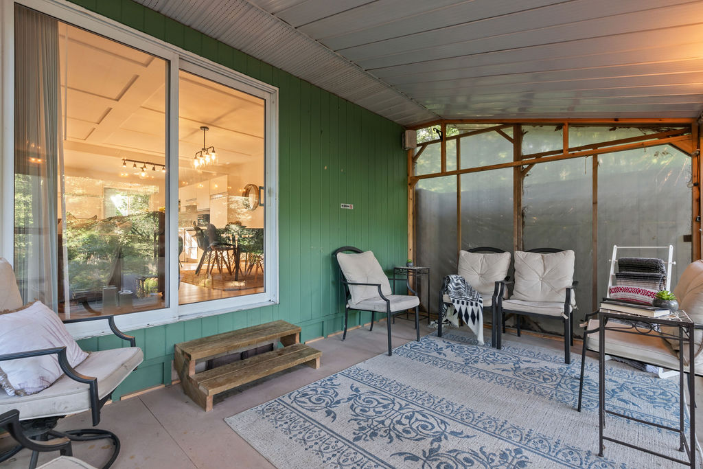 Three white chairs sit next to the teal wood cottage