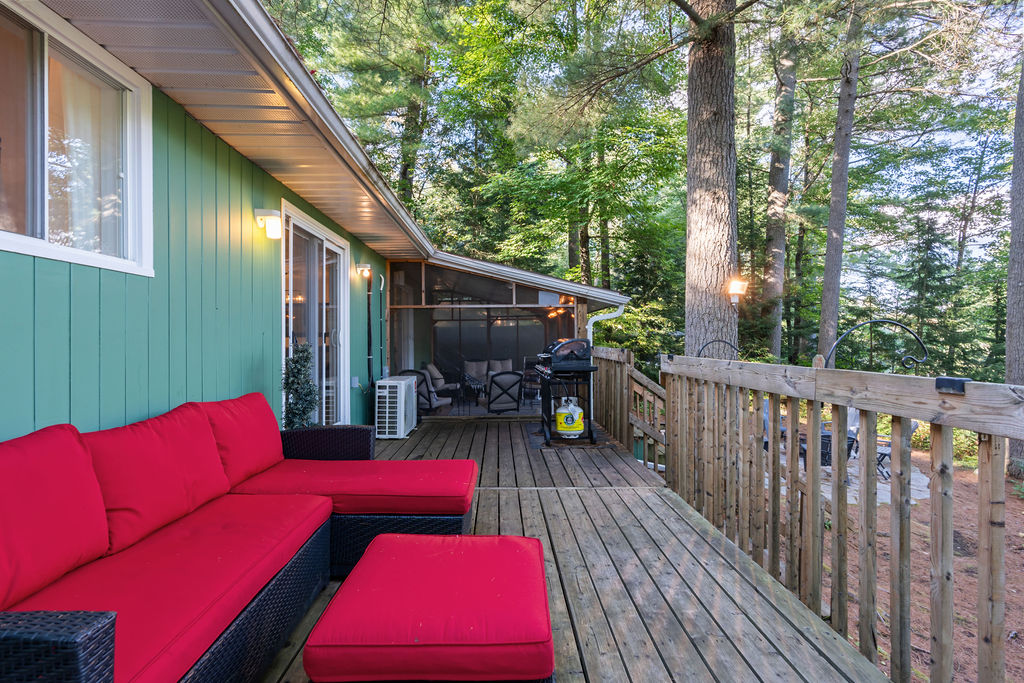 Red patio couches face the deck. At the other end, a screened-in porch