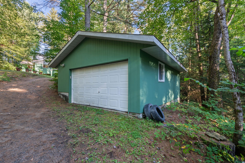 A teal garage with a white door in the forest