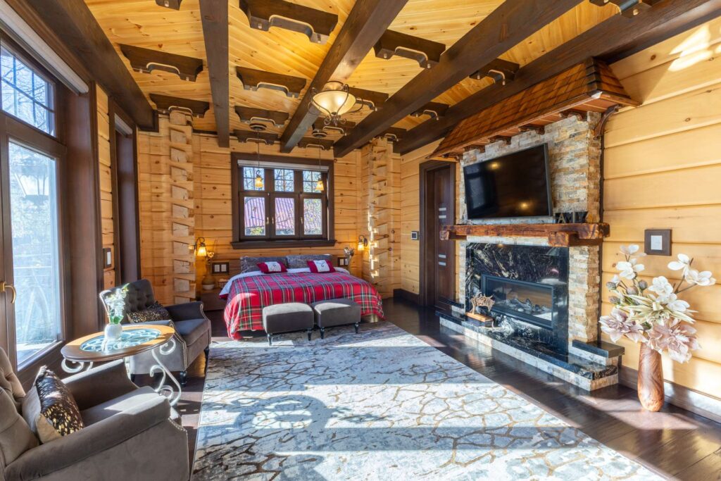 A red bed in a spacious bedroom with a fireplace on the right