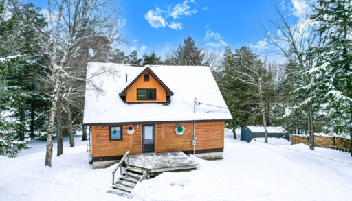 A red-brown cottage with black trim in the snow