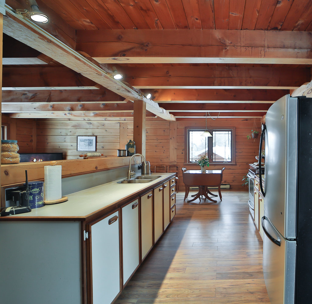 A wood kitchen with a light-coloured kitchen island facing a stainless steel fridge