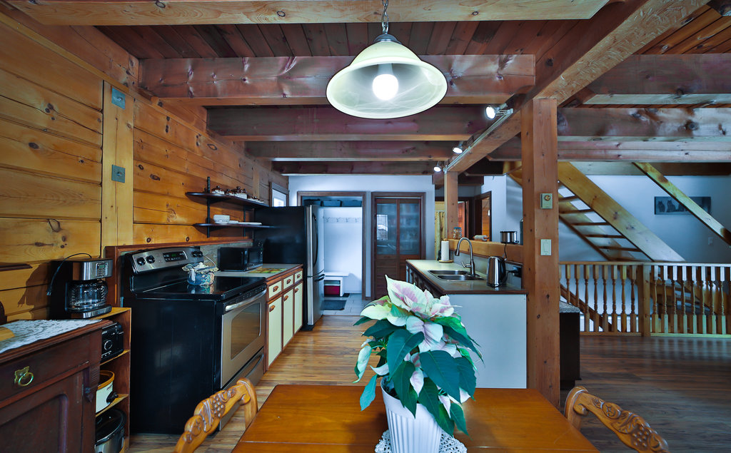 Stainless steel appliances face a light-coloured kitchen island in a wood-paneled room