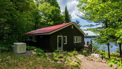 A grey paneled cottage with a red roof