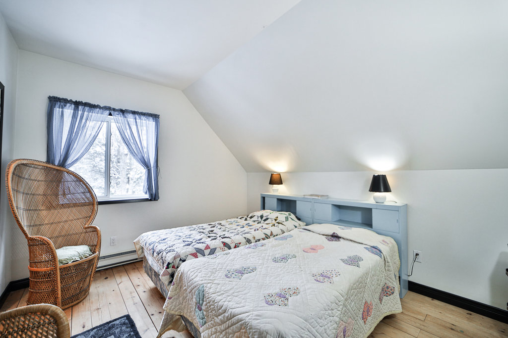 Two beds with white floral quilts behind light blue cabinets in a white room