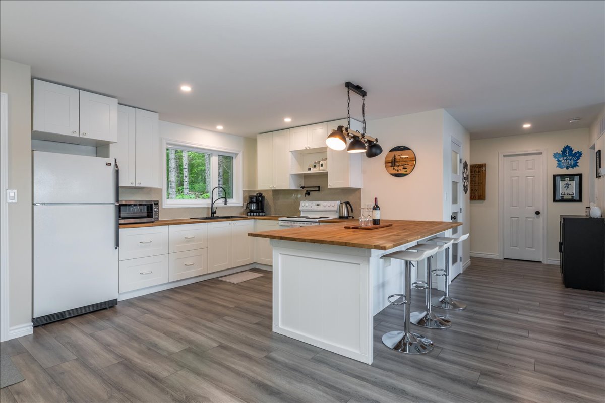 A white kitchen with grey hardwood floors and a wood island
