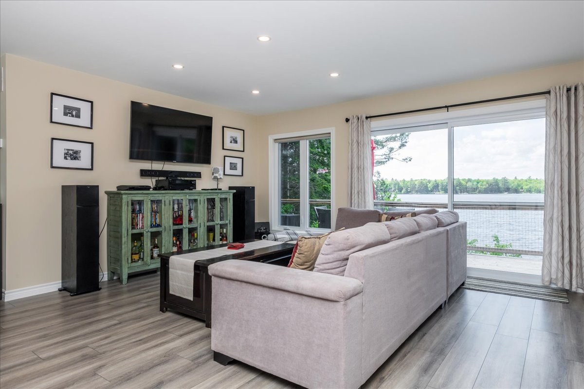 A grey couch faces a mounted TV and green media unit.