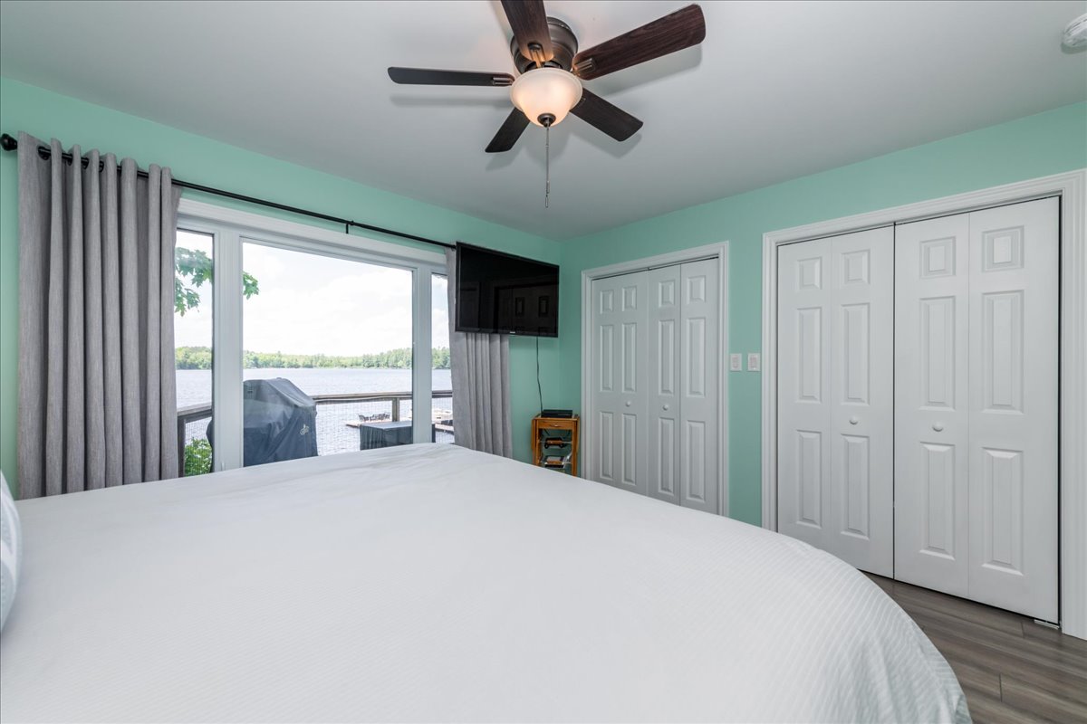 A large white bed on a grey bed frame in a teal room faces white closets
