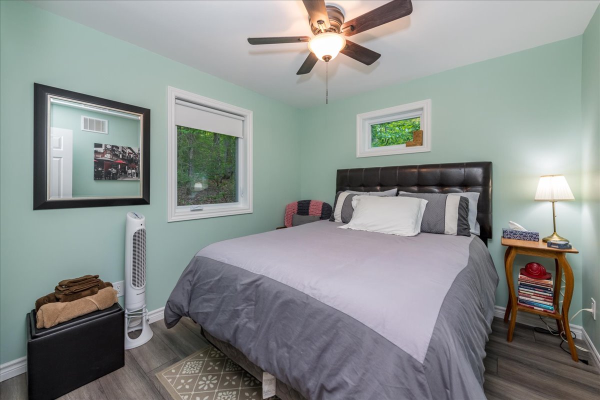 A grey bed in a teal room with an overhead ceiling fan
