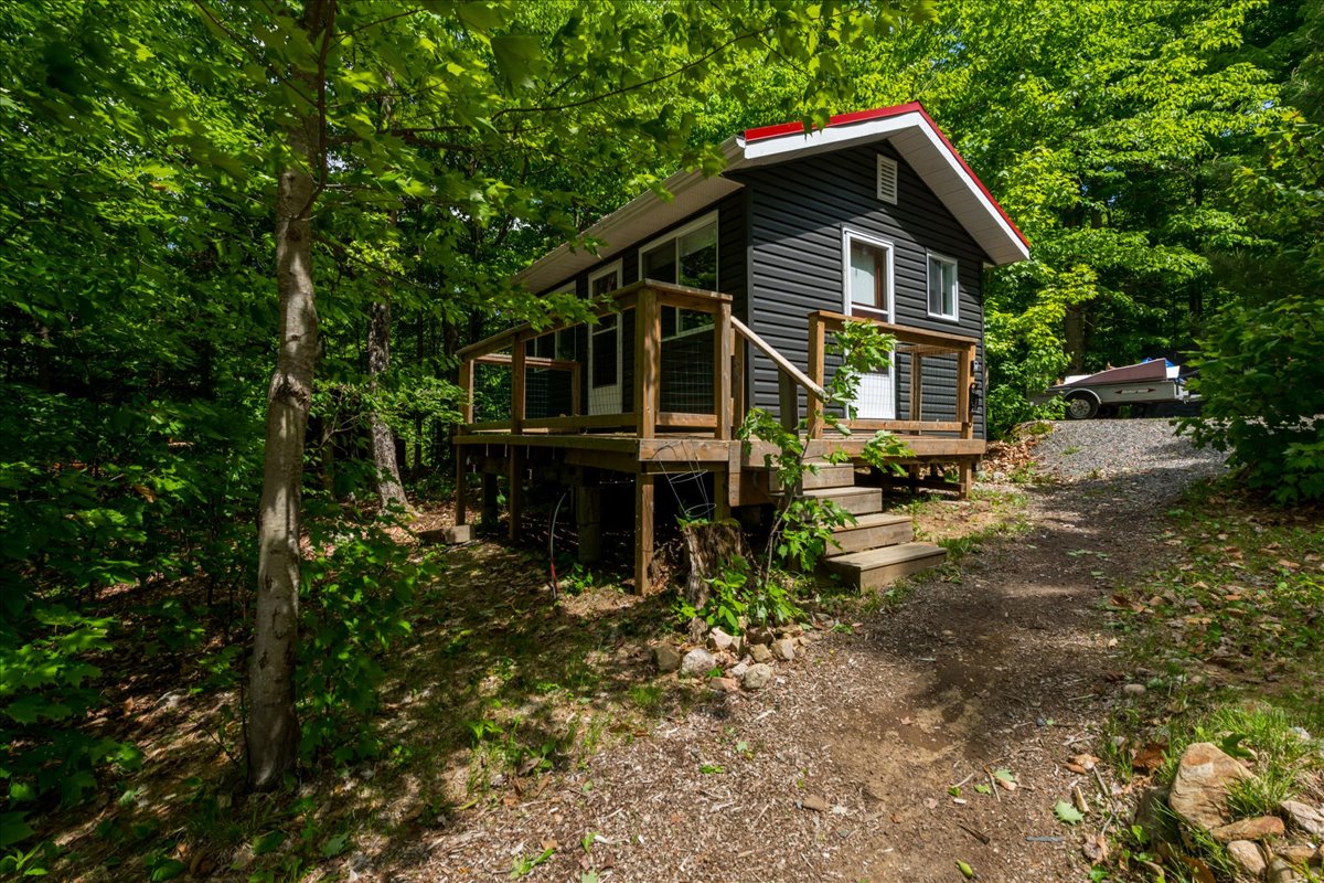 A small grey paneled building with wood steps