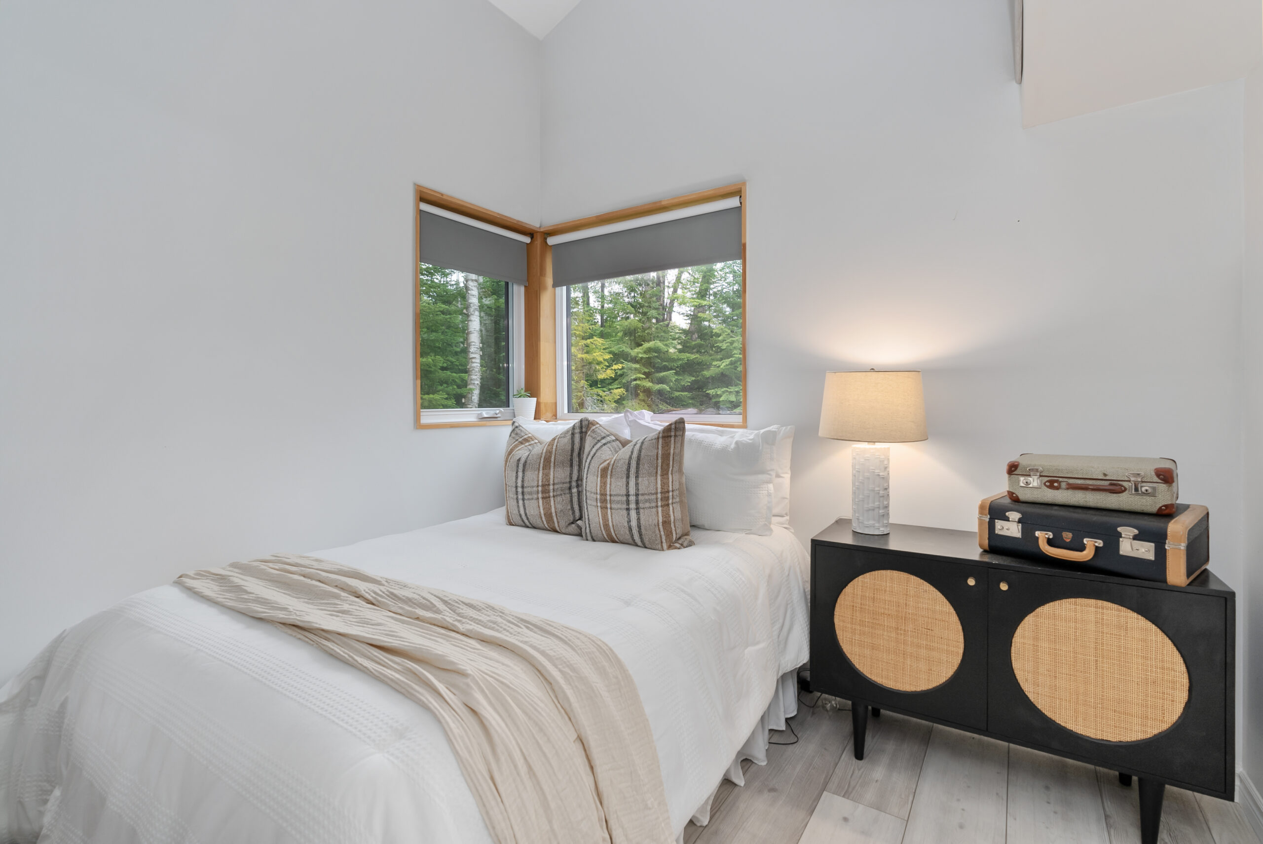 A white bed with plaid throw pillows in a white room