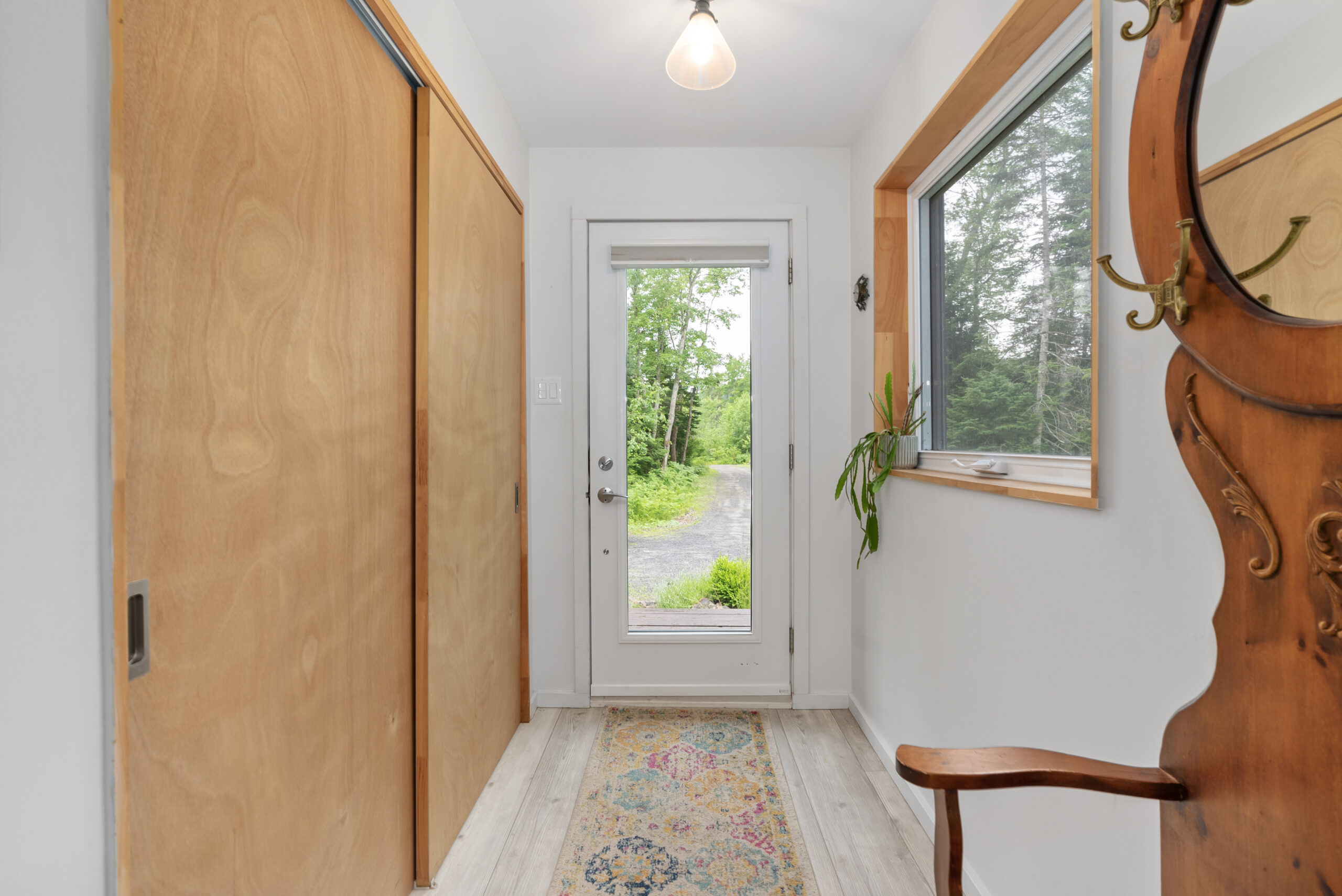 A white-framed glass door at the end of a white hallway