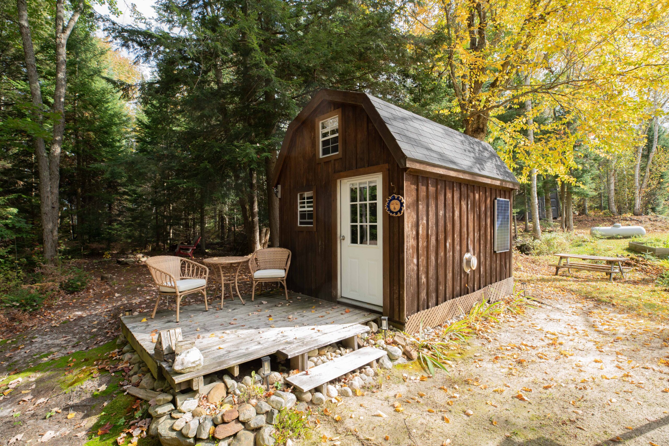 A brown barn-shaped bunkie with a small patio