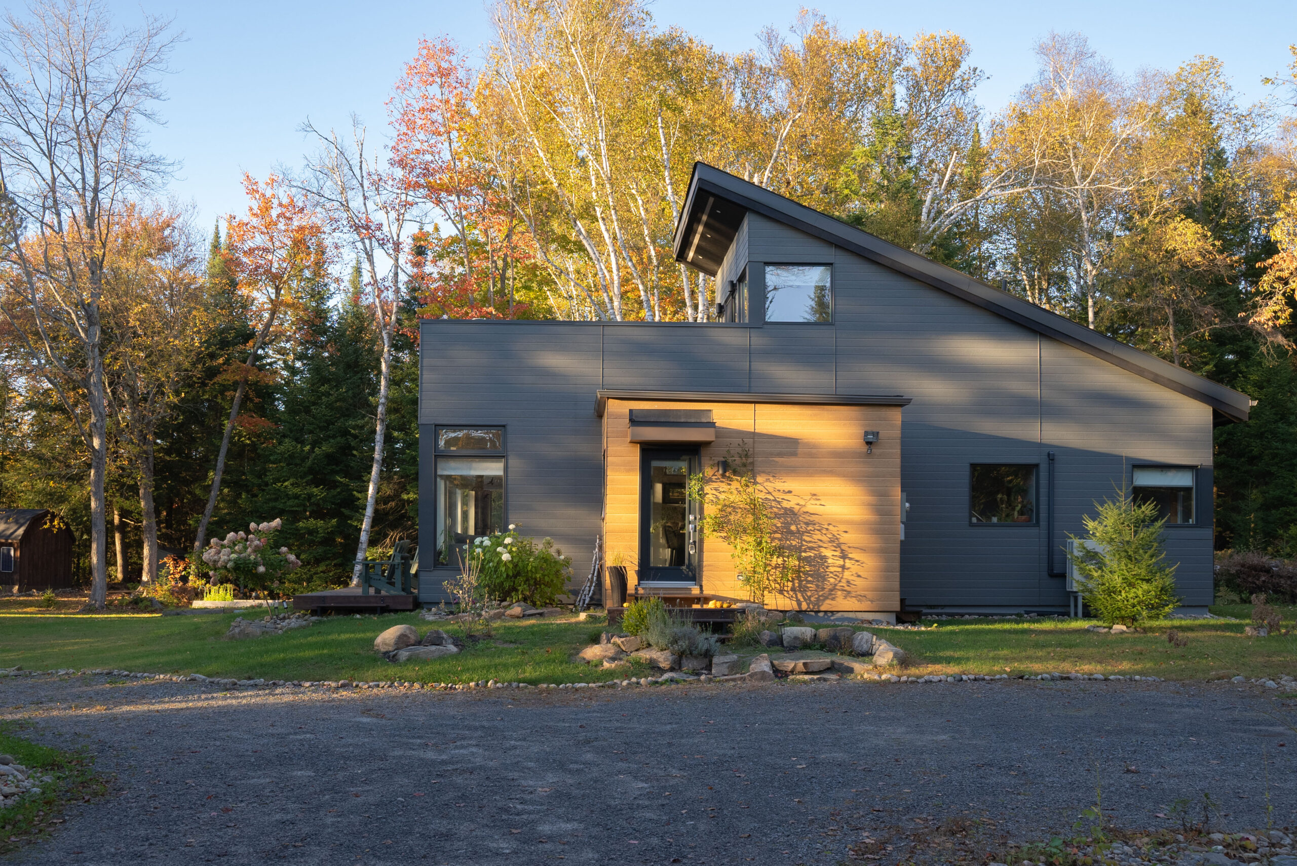 A two-story grey cottage with a lower level patio