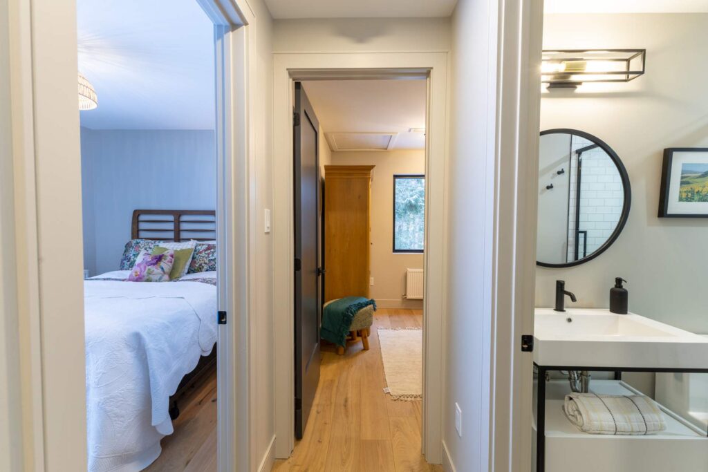 A hallway with doorways to two bedrooms and a bathroom